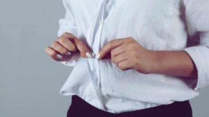 persona che si abbottona la camicia