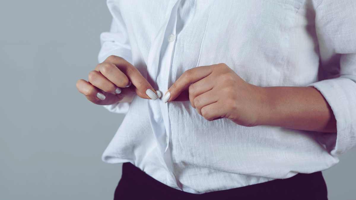 persona che si abbottona la camicia